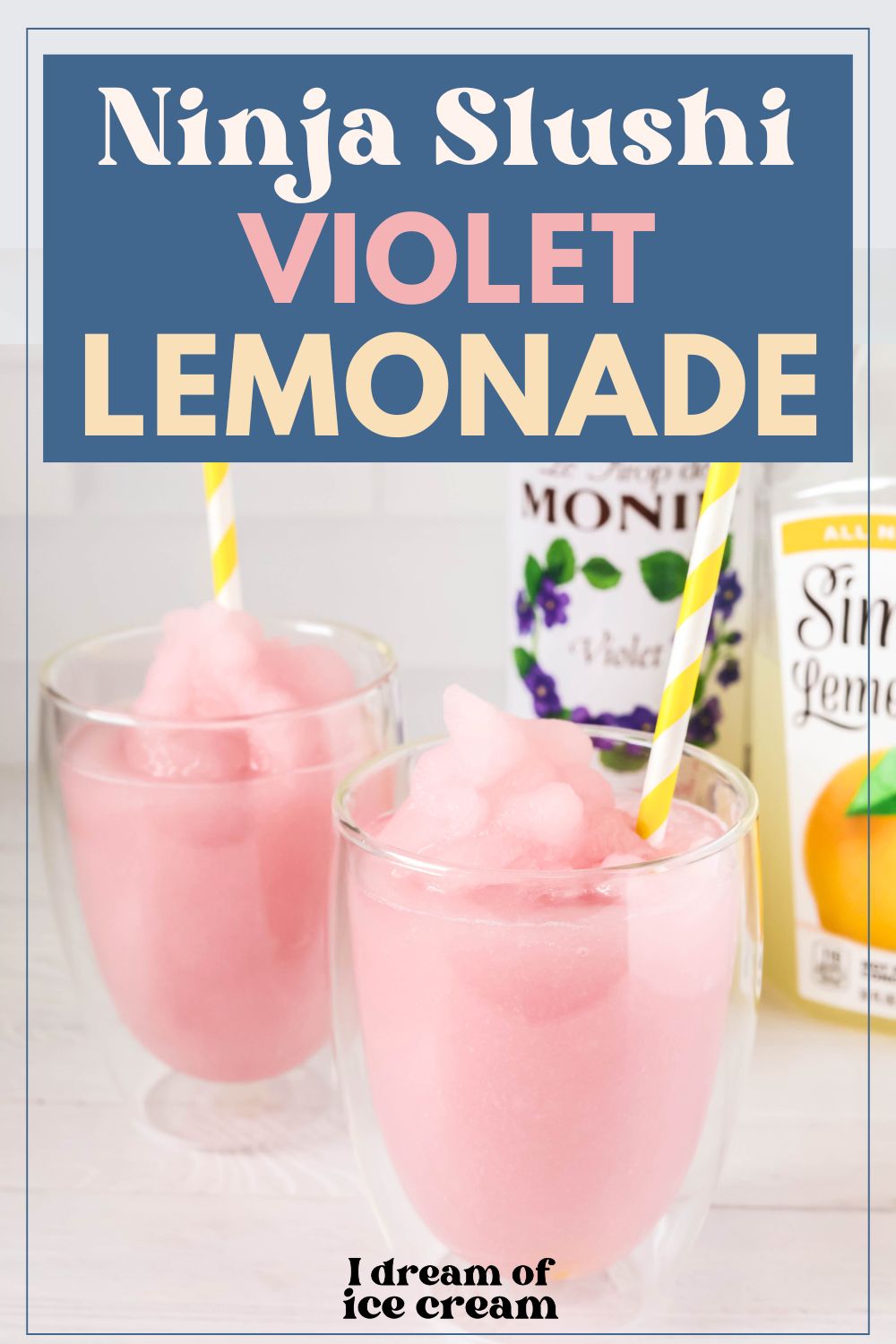 Two glasses of violet lemonade slush in the foreground, with bottles of violet syrup and lemonade in the background.