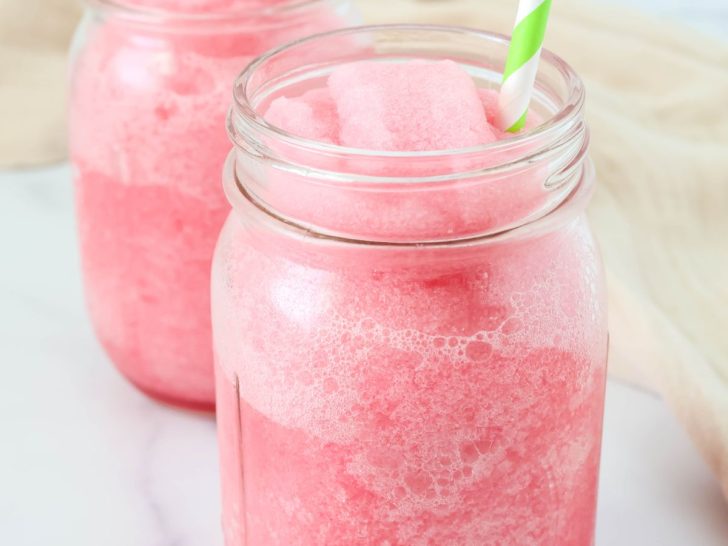 Ninja Slushi hibiscus limeade served in two Mason jar glasses with green and white straws.