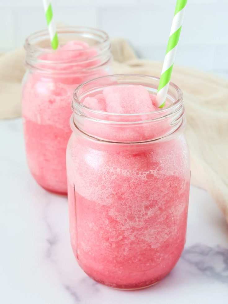 Ninja Slushi hibiscus limeade served in two Mason jar glasses with green and white straws.